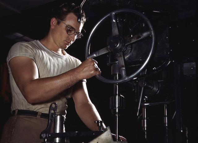 Un empleado en la sección de prensa con un taladro enorme taller de North Americans realiza los agujeros de montaje, en Inglewood, California, en octubre de 1942