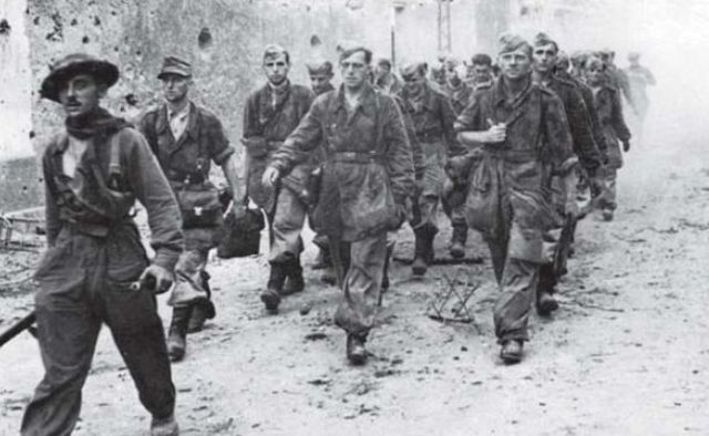 Prisioneros alemanes pertenecientes a la Hermann Goering Division son escoltados por un soldado británico del 2º Comando